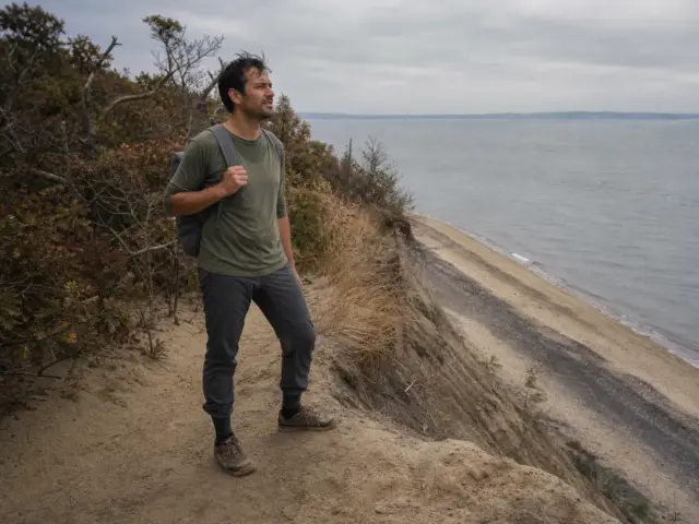 0-places-to-hike-long-island-sunken-meadow-bluff Hiker on the bluff trail above the beach at Sunken Meadow State Park, one of the best places to hike Long Island.