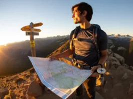 A hiker on a mountain ridge at sunrise consults a map, symbolizing the process of choosing a Colorado hiking trip from many options.