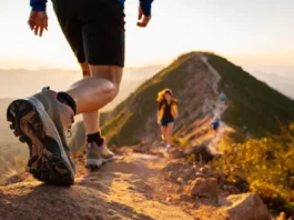 A hiker walks on a mountain trail, showcasing a detailed hiking boot, representing a guide to understanding hiking boot materials, fit, and types.