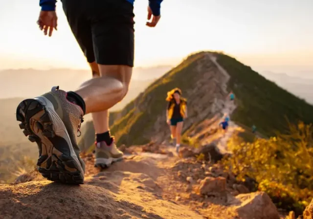 A hiker walks on a mountain trail, showcasing a detailed hiking boot, representing a guide to understanding hiking boot materials, fit, and types.