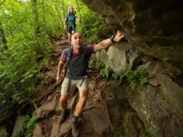 Two diverse hikers navigate a challenging, rocky scramble on the Bear Mountain trail, illustrating the difficulty of the hike.