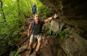 How Hard is the Bear Mountain Hike? A Trail Guide Two diverse hikers navigate a challenging, rocky scramble on the Bear Mountain trail, illustrating the difficulty of the hike.