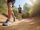 Trail Runners vs. Hiking Shoes: Which Should You Wear? Two hikers on a trail, one in trail runners and the other in hiking shoes, visually representing the choice between different hiking footwear.