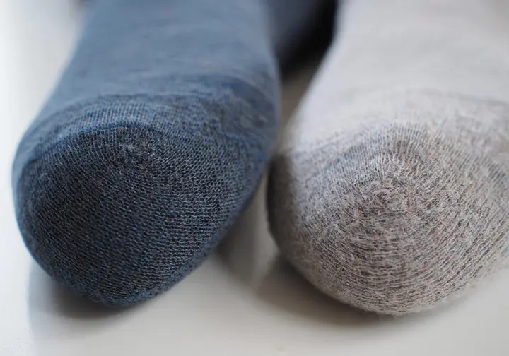 Close-up of a merino wool hiking sock and a synthetic hiking sock, illustrating the anatomy of high-performance hiking socks and their materials.