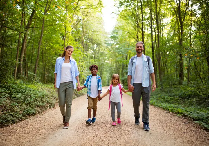 A family walks happily on a flat, well-maintained trail through a sun-dappled forest, illustrating Vancouver's best easy hikes for beginners and families.