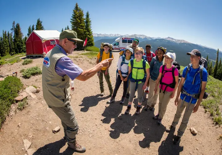 A professional guide leads a group of diverse hikers on a Colorado trail, illustrating commercial guided hiking services.