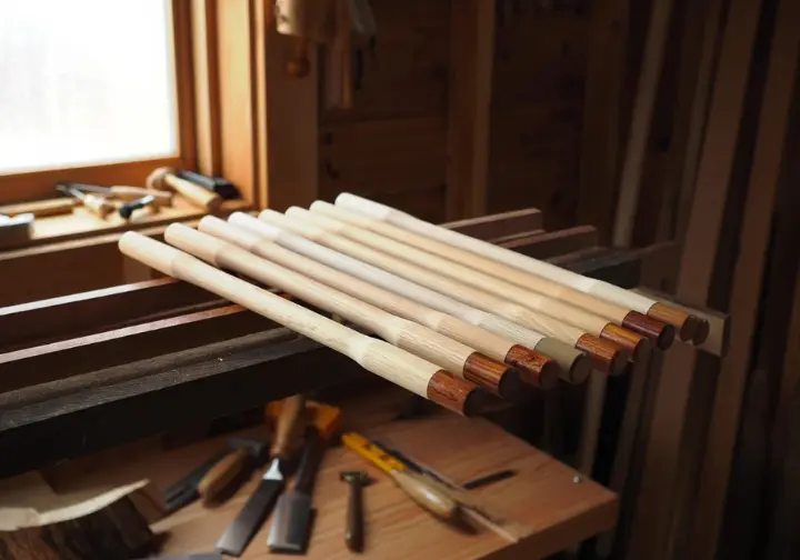 Debarked wooden hiking stick blanks are air-drying on a rack in a shed, illustrating the curing process for making a hiking stick.