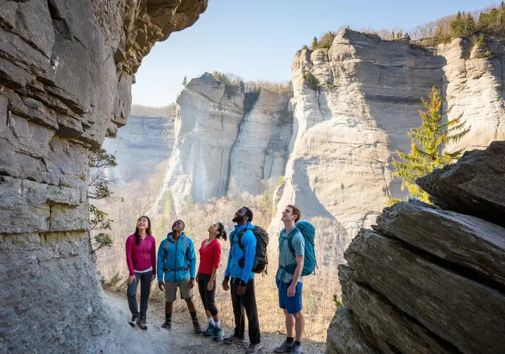The dramatic Shawangunk Conglomerate cliffs in Minnewaska State Park, illustrating the park's unique geological environment with hikers for scale.