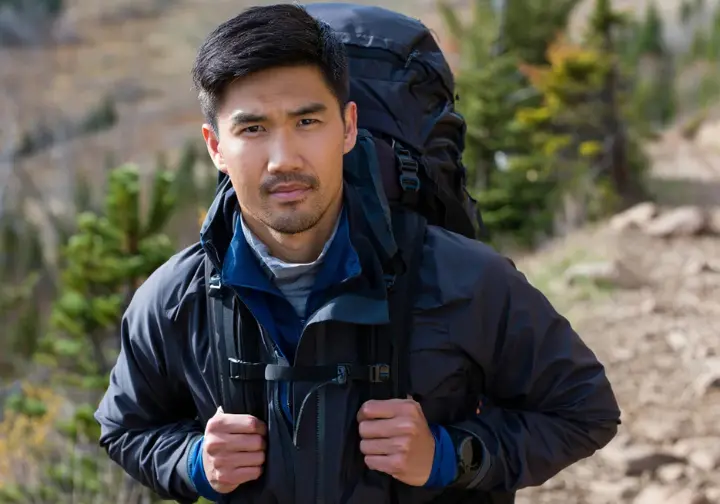 A prepared hiker wearing a complete layering system and backpack on a mountain trail, demonstrating what to wear and pack for Vancouver trails.
