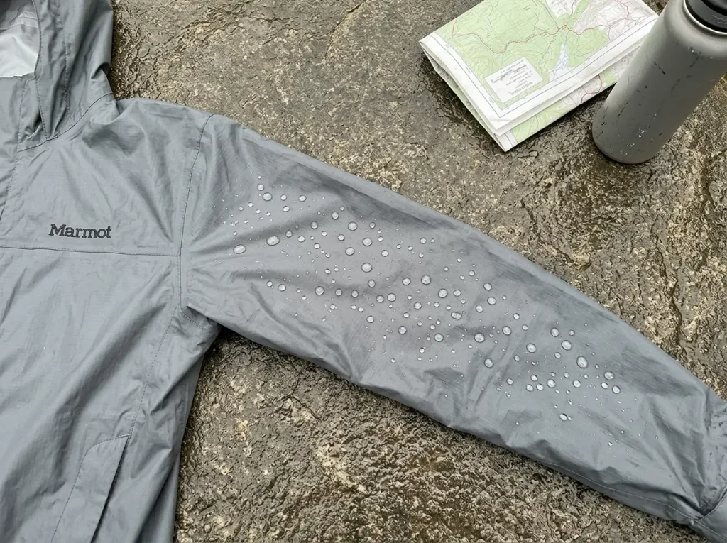 Water beading on the sleeve of a Marmot PreCip Eco rain jacket laid over a wet rock