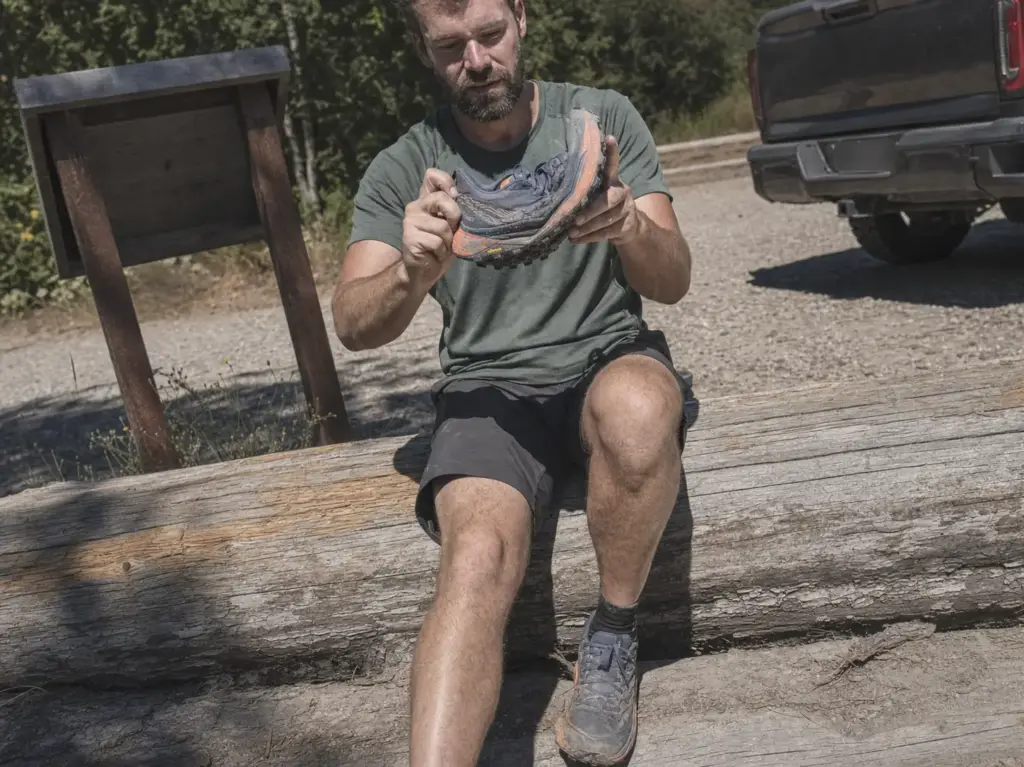 Hiker holding a trail running shoe showing its flexible sole, mesh upper and deep lug pattern