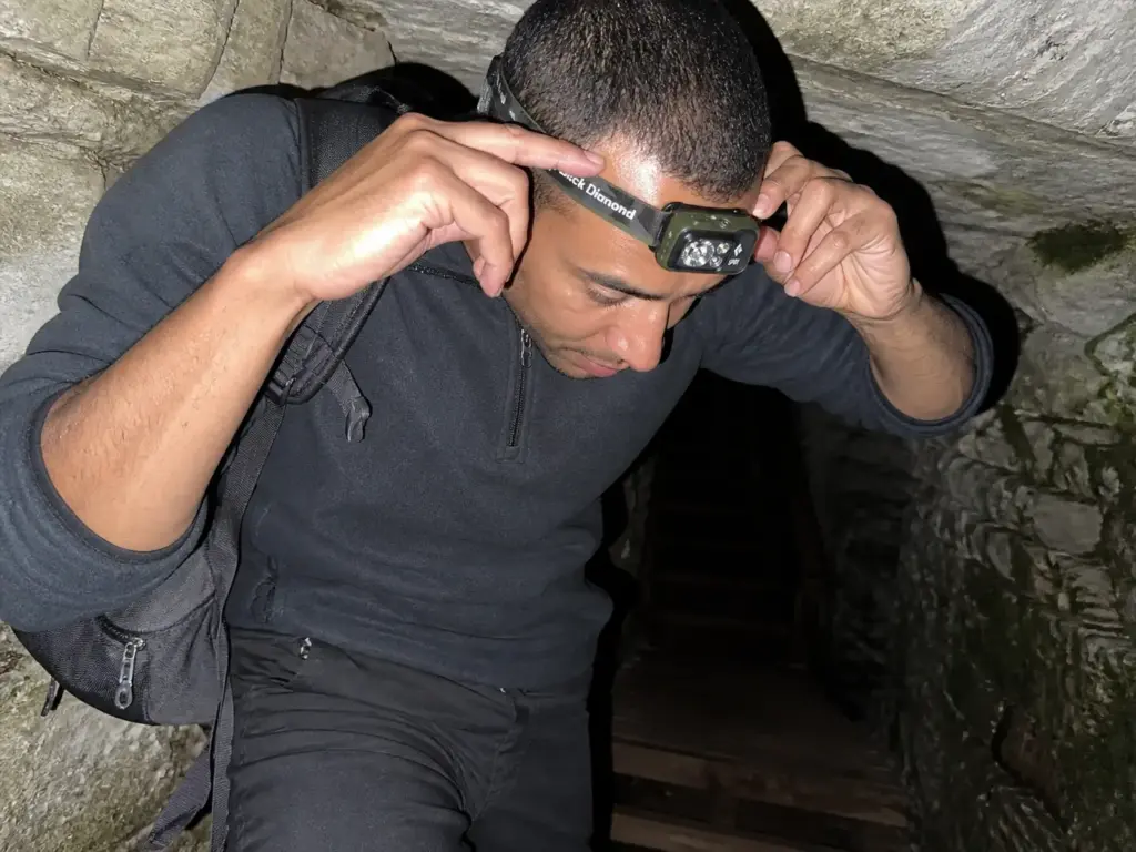Hiker adjusting a headlamp before entering a dark crevice on the Ice Cave Trail