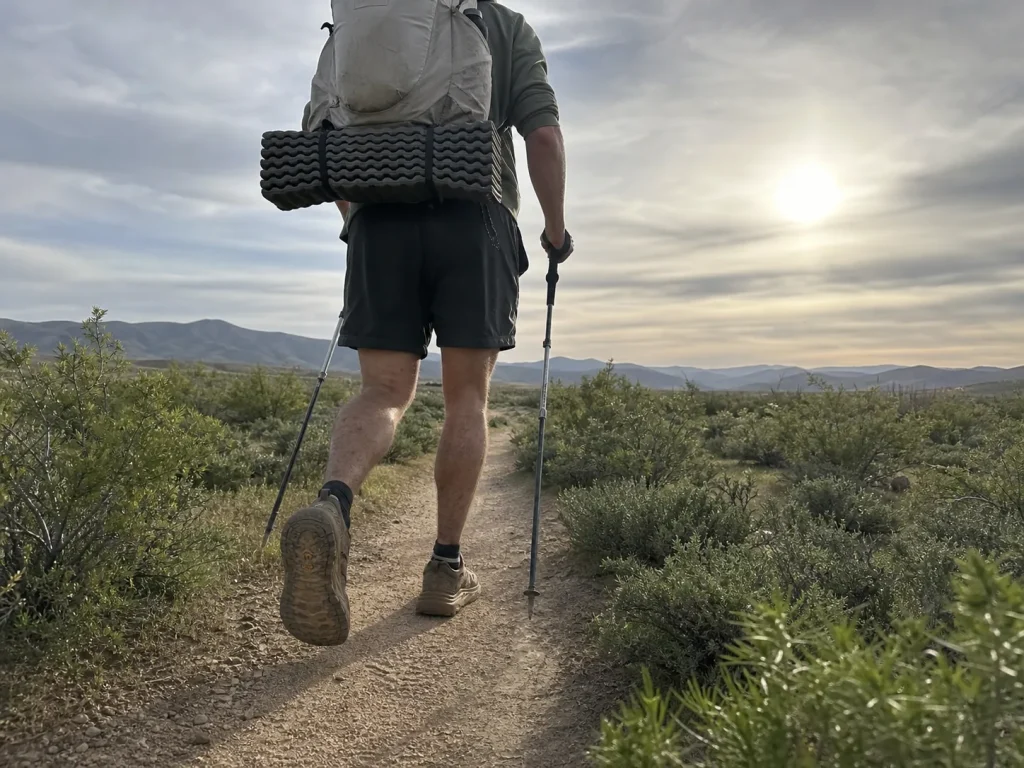 Thru-hiker walking a long trail in low-cut trail shoes with a light backpack