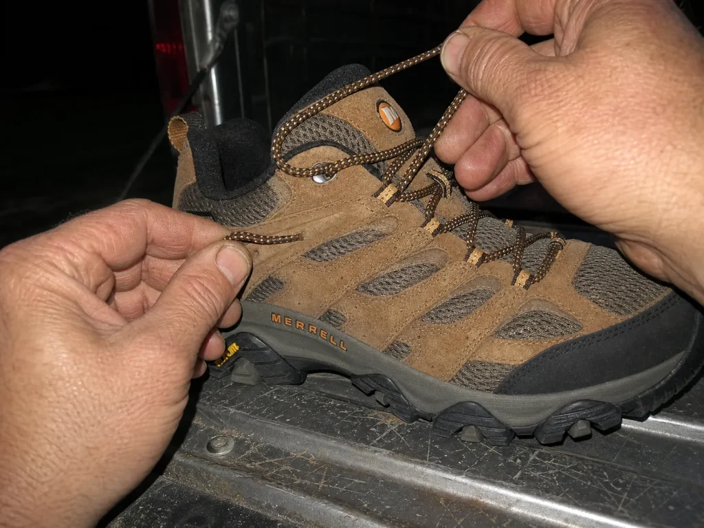 Close-up of heel-lock lacing on a low-cut hiking shoe at a tailgate at dusk