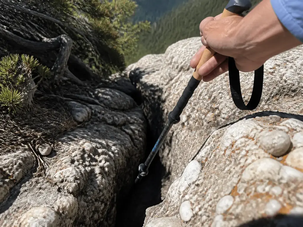 Trekking pole tip probing a shaded rock crevice on a Minnewaska talus slope
