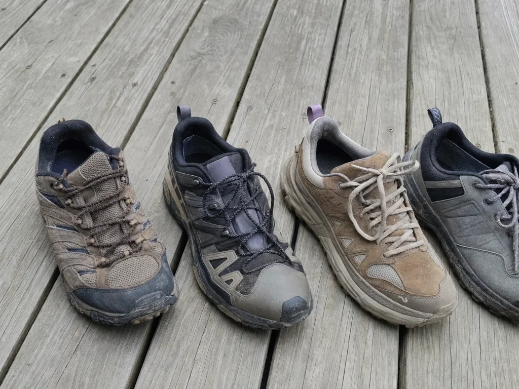Row of budget to premium low-cut hiking shoes lined up on a porch board