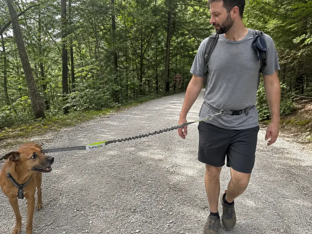 Hiker walking a leashed dog on a hands-free waist leash on a Minnewaska carriage road
