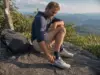 Best Thru-Hiking Shoes That Actually Reach 700 Miles Thru-hiker checking worn Altra Lone Peak trail runners on an Appalachian Trail ridgeline