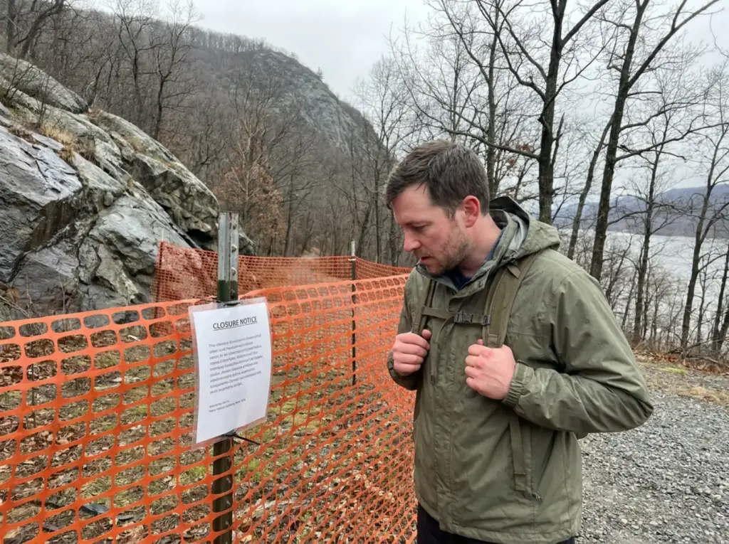 Closed Breakneck Ridge trailhead fenced off below the Hudson Highlands ridgeline in New York