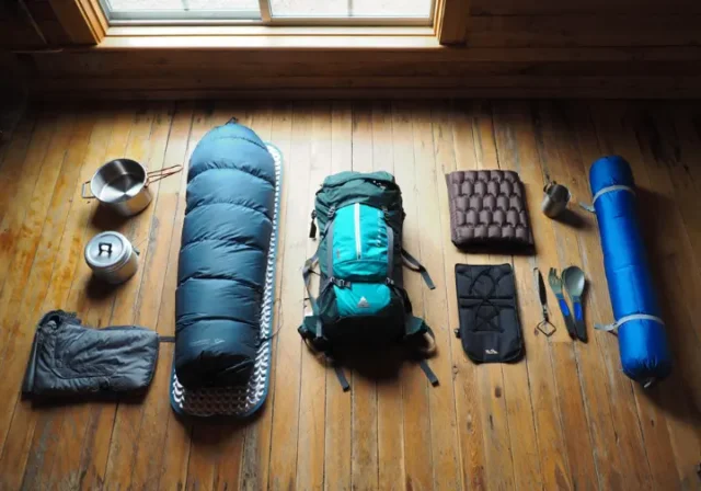 A flat lay of backpacking gear showing a progression from beginner items on the left to expert ultralight equipment on the right.
