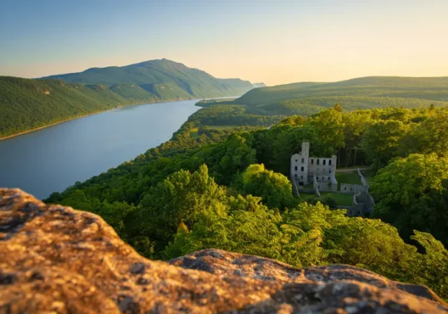 Expansive view from Bull Hill in Cold Spring, NY, showing the Hudson River and the Cornish Estate ruins at golden hour.