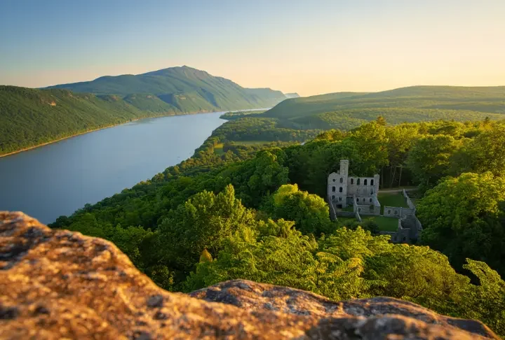 Expansive view from Bull Hill in Cold Spring, NY, showing the Hudson River and the Cornish Estate ruins at golden hour.