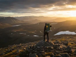 Lone backpacker overlooking a vast, mountainous Arctic landscape, symbolizing survival and resilience in Gates of the Arctic National Park.