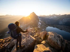 A prepared hiker overlooks a stunning mountain vista during a sunrise, representing the best of good hikes in Colorado.