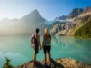 Joffre Lake BC: A Guide to Passes, Camping & 3 Lakes Two hikers look out over the stunning turquoise water of Joffre Lake towards the Matier Glacier in British Columbia.