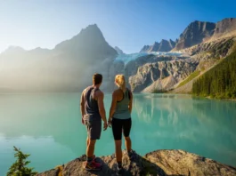 Two hikers look out over the stunning turquoise water of Joffre Lake towards the Matier Glacier in British Columbia.