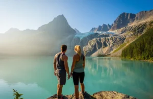 Joffre Lake BC: A Guide to Passes, Camping & 3 Lakes Two hikers look out over the stunning turquoise water of Joffre Lake towards the Matier Glacier in British Columbia.