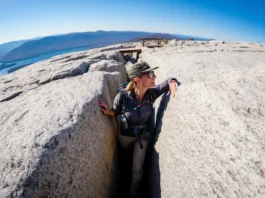 A hiker emerges from the narrow Lemon Squeeze rock scramble at Mohonk Preserve, looking out at the panoramic view of the Hudson Valley from the clifftop.