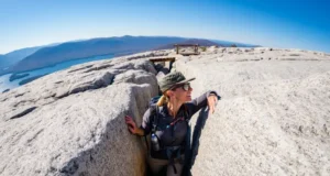 Mohonk Preserve Lemon Squeeze: The Definitive Guide A hiker emerges from the narrow Lemon Squeeze rock scramble at Mohonk Preserve, looking out at the panoramic view of the Hudson Valley from the clifftop.