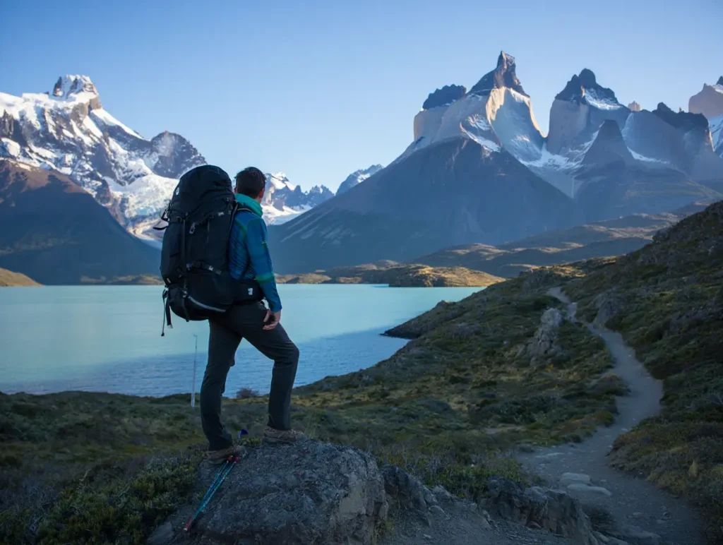 A hiker looking out at the Torres del Paine massif, planning their route on the O Circuit in Patagonia at sunrise.