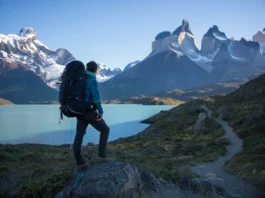 A hiker looking out at the Torres del Paine massif, planning their route on the O Circuit in Patagonia at sunrise.
