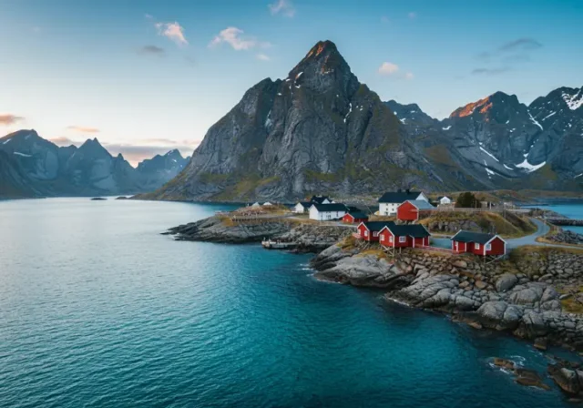 Jaw-dropping views while hiking in the Lofoten Islands, featuring jagged peaks rising from turquoise fjords and red rorbuer cabins.