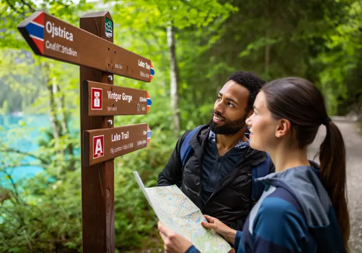 A couple of hikers use a map to plan their route at a trail signpost near Lake Bl
