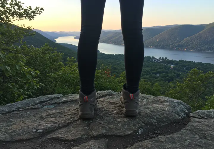 Hiker's perspective overlooking a hidden gem view on Breakneck Ridge, with partial views of the Hudson River and surrounding landscape.