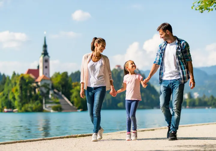 A happy family enjoys an easy, family-friendly walk on the paved trail around Lake Bled, Slovenia.