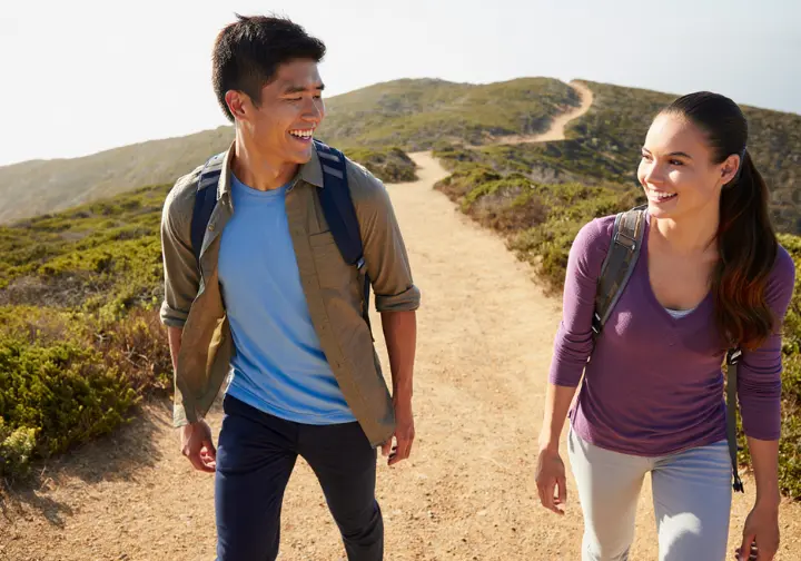 A smiling couple enjoys a walk on a wide, easy beginner trail in Southern California, building a strong foundation for their hiking skills.