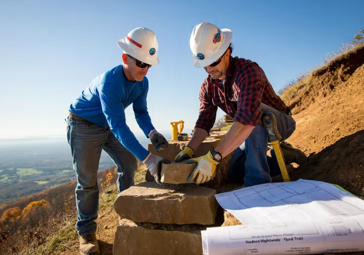 Skilled trail workers building a new, sustainable stone staircase on Breakneck Ridge as part of the future Hudson Highlands Fjord Trail project.
