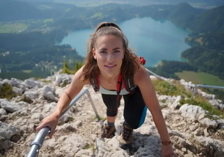 A hiker stands at a rocky viewpoint above Lake Bled after a moderate hike, enjoying the panoramic view.