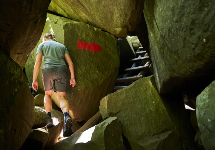 A hiker follows the red arrow trail markers through the challenging boulder maze of The Labyrinth at Mohonk Preserve.