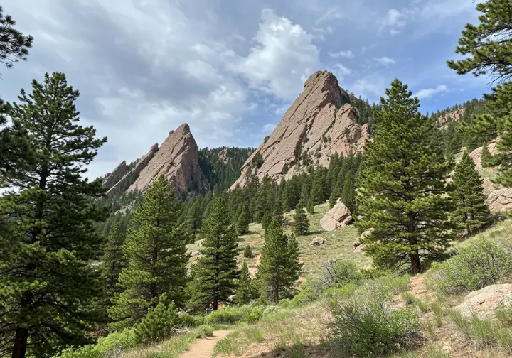 The Flatirons rock formations in Boulder, Colorado, with a hiking trail in the foreground, representing Boulder's backyard adventure