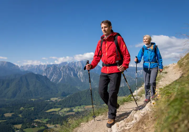 Two experienced hikers on a challenging, high-altitude trail in the Julian Alps near Lake Bled.