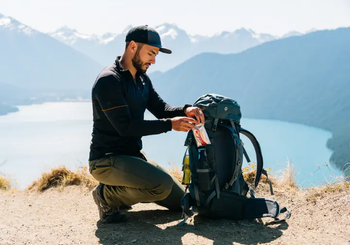 A responsible hiker packs out his trash while taking a break at a viewpoint at Joffre Lakes, practicing Leave No Trace.