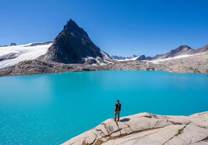 A hiker looking at the iconic view of the turquoise Garibaldi Lake and Black Tusk peak in the Sea-to-Sky corridor, BC.