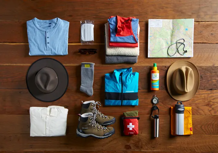 Essential Colorado hiking gear, including boots, layers, map, compass, and safety items, neatly organized in a flat lay to show what to pack.