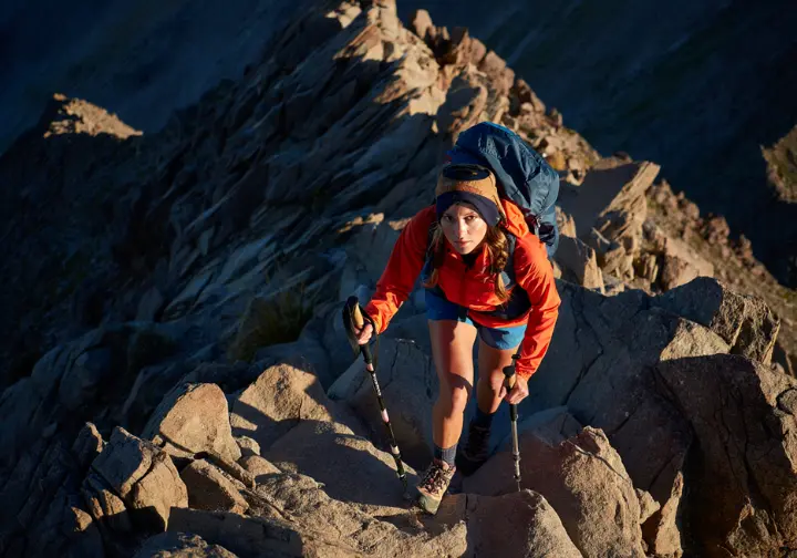 A skilled female hiker masters a difficult and exposed rocky ridge on a high-altitude Southern California mountain trail.