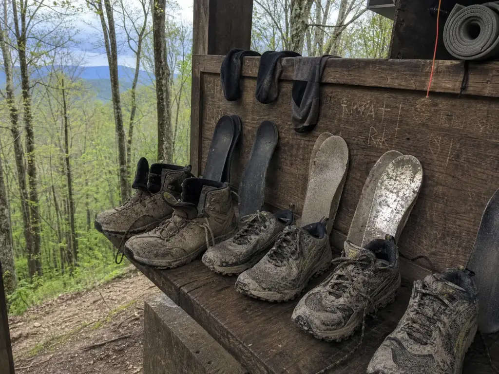 Worn hiking boots and trail runners lined up at an Appalachian Trail shelter